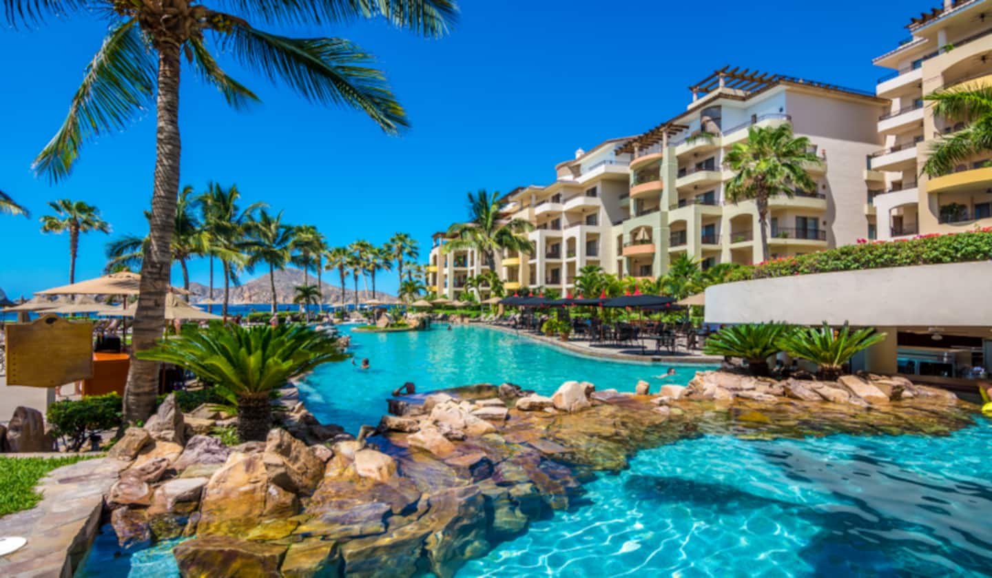 Turquoise resort pool surrounded by palms at Villa La Estancia Cabo